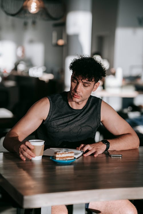 Free A Man in Black Tank Top Sitting at the Table Stock Photo