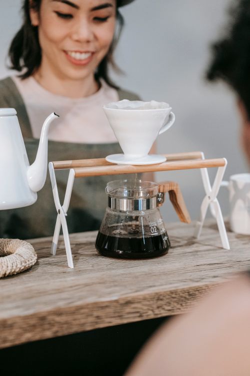 Free A barista smiles while preparing coffee with a V60 dripper in a cafe setting. Stock Photo