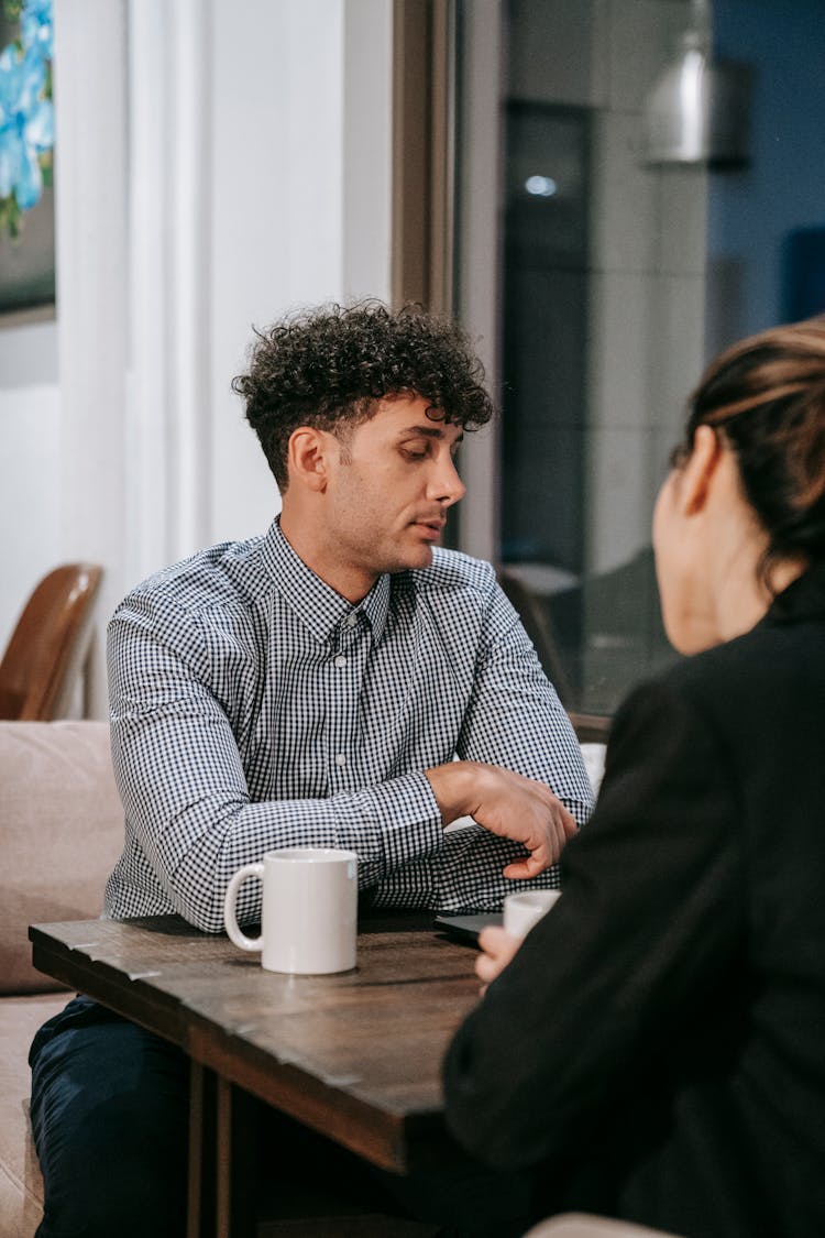 Man In Checkered Button Up Shirt Having Coffee With A Woman