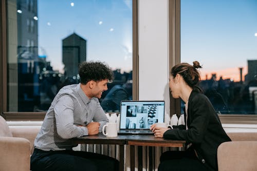 Free A Man and a Woman Looking at a Laptop on a Table Stock Photo