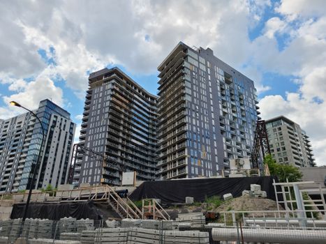 High-rise buildings under construction in an urban cityscape with cloudy sky.