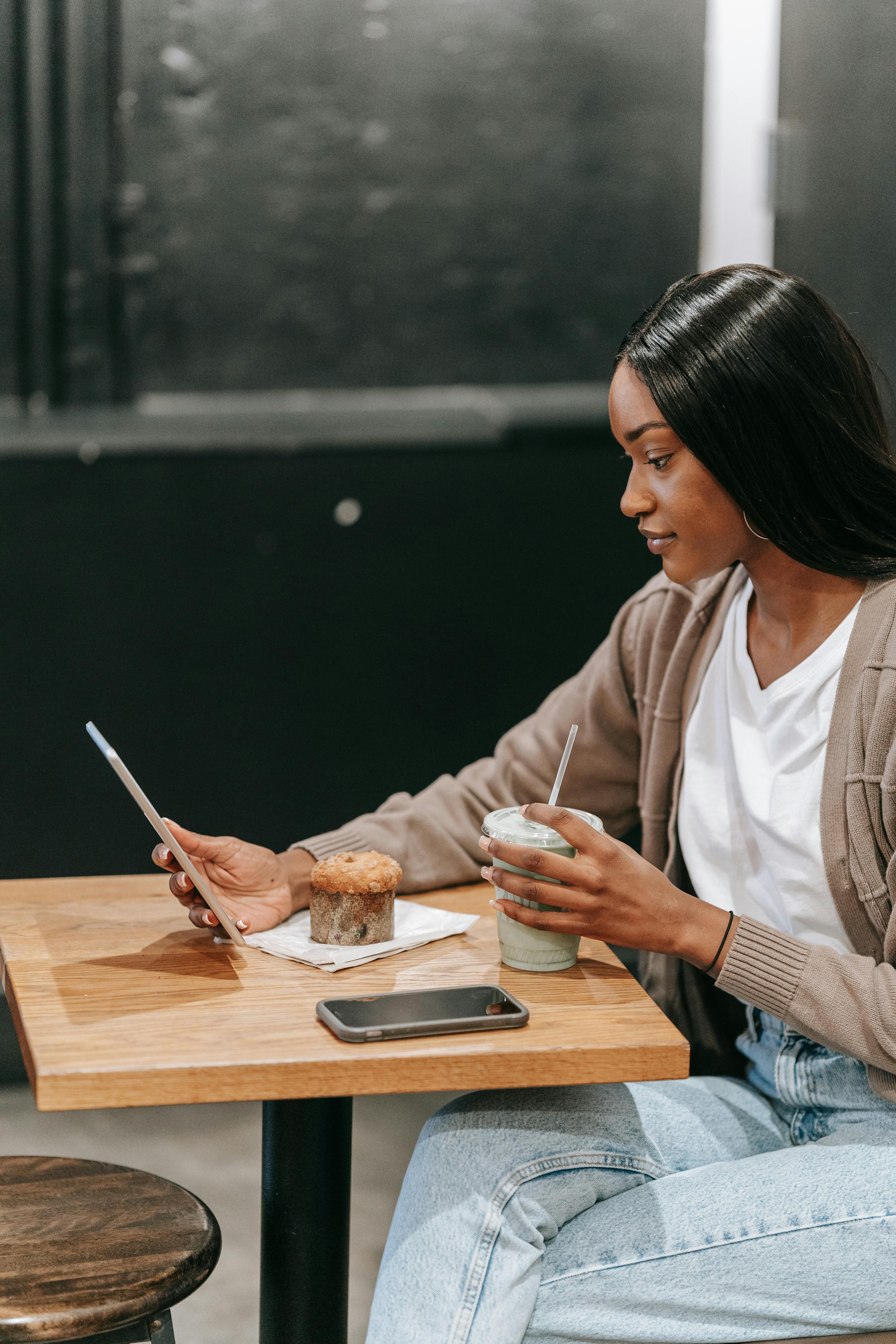 woman drinking coffee in cafe using mobile