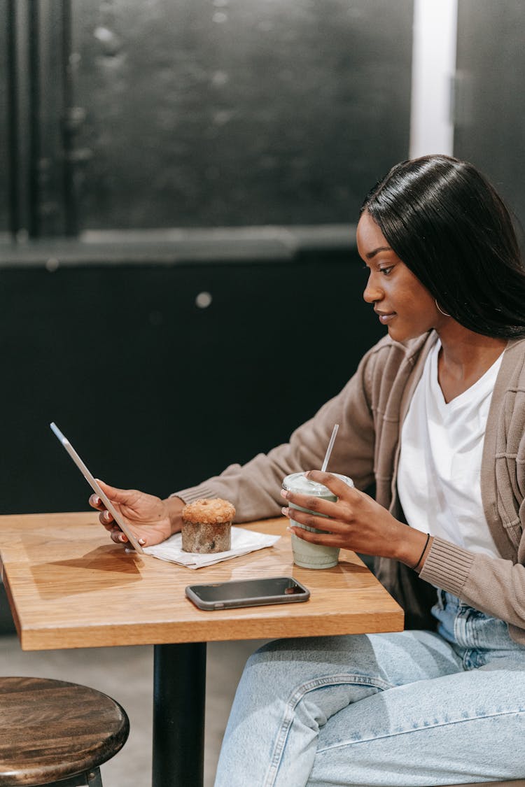 Woman Drinking Coffee In Cafe Using Mobile