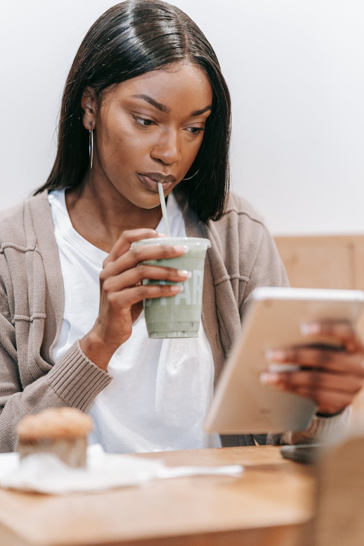 Woman Drinking And Looking At Tablet