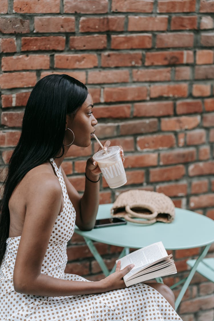 Woman Sitting At Cafe Table Reading Book