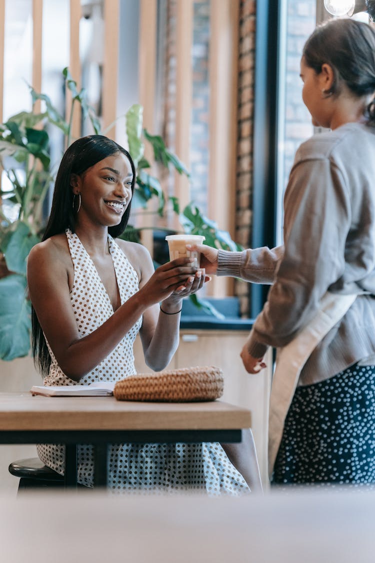 A Person Handing A Drink To A Happy Woman