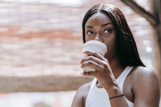 Close-up of a woman drinking coffee from a disposable cup in an outdoor setting.