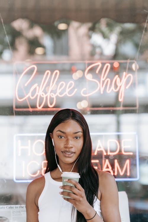 A Woman in White Tank Top Holding a Coffee Cup