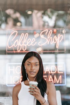 A trendy woman with earphones enjoying a coffee in a modern cafe setting.
