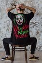 Man in Black and Red Crew Neck T-shirt Sitting on Black Wooden Seat