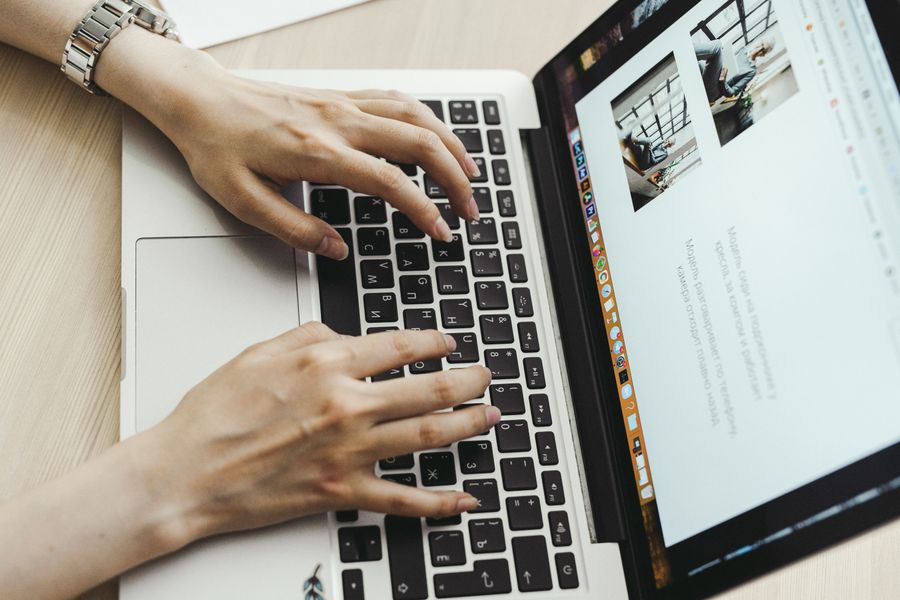 Close-up of hands typing on a laptop keyboard in an office setting.