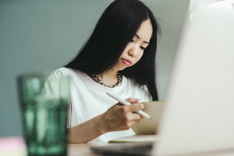 Woman In White Crew Neck Shirt Holding A Pen And A Notebook