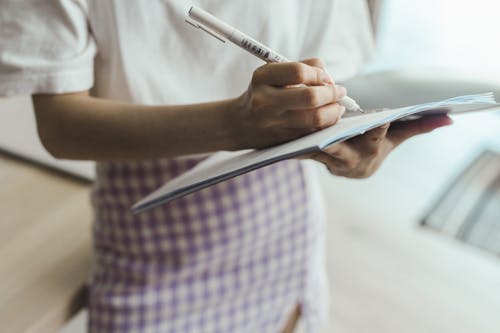 Free Person in White Shirt Writing on Notebook Stock Photo