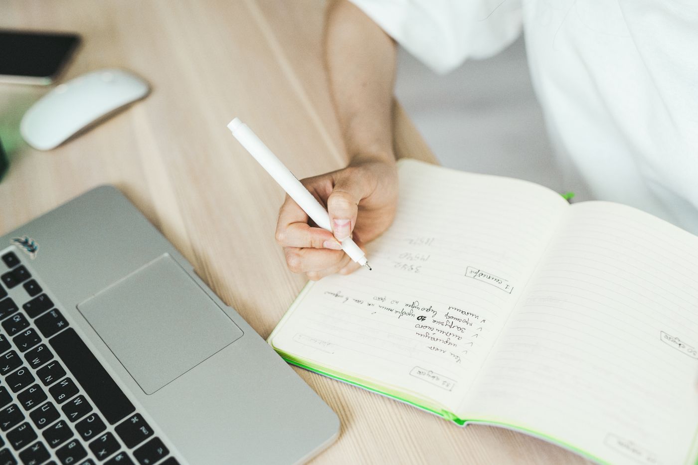 Person hält berufliche Beobachtungen und nächste Schritte in einem Notizbuch fest