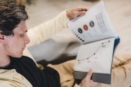 Adult man reviewing business charts in a document, focused on growth strategy.