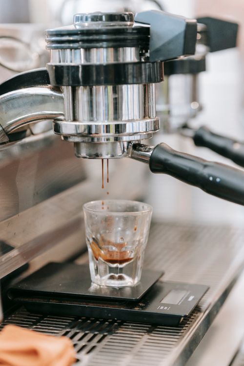 Free A detailed view of an espresso machine pouring a fresh espresso shot into a glass. Stock Photo