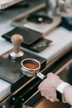 Close-up of barista preparing espresso with a portafilter in a modern coffee shop environment.