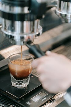 Close-up of espresso being freshly brewed from a machine into a shot glass.