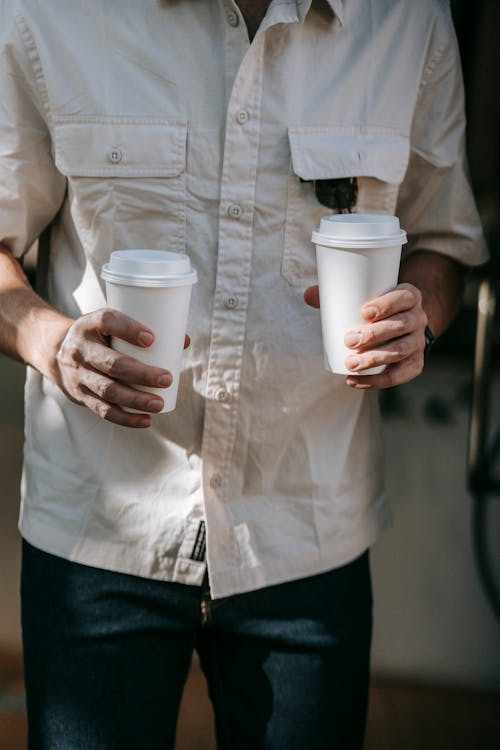 Person in White Button Up Shirt Holding White Disposable Cups