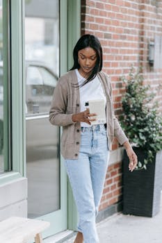 Stylish young woman enjoying coffee and a book outside a cafe.
