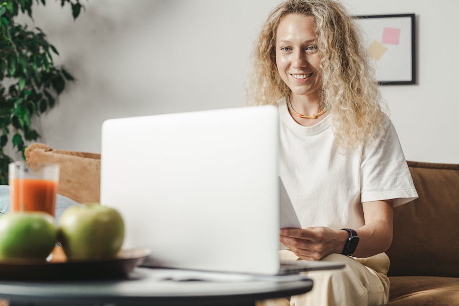 How QuickBooks Solves Tax Tracking for Freelancers A woman with curly hair smiling as she works on her laptop indoors, complementing a relaxed freelance lifestyle.