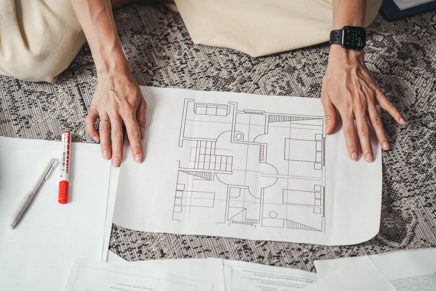 Plan d’étage tenu devant un espace intérieur en rénovation