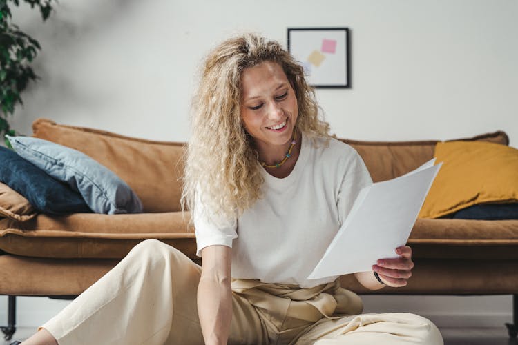 Blonde Woman Smiling While Holding Papers  