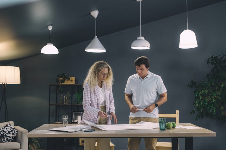 Coworkers Standing And Looking At A Project Lying On A Table 