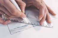 Close Up Photo of Person Drawing Lines on Paper with a Ruler and Pen