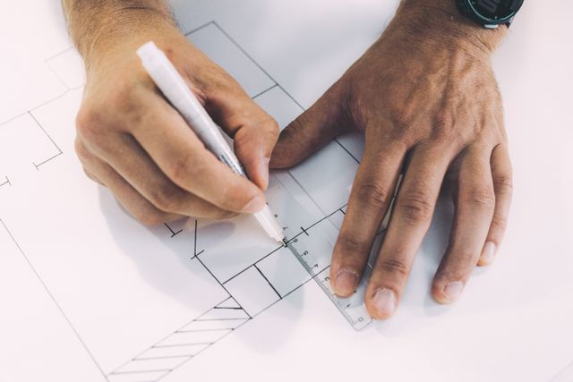 Mains traçant un plan à la règle lors de la phase d'esquisse d'un jardin