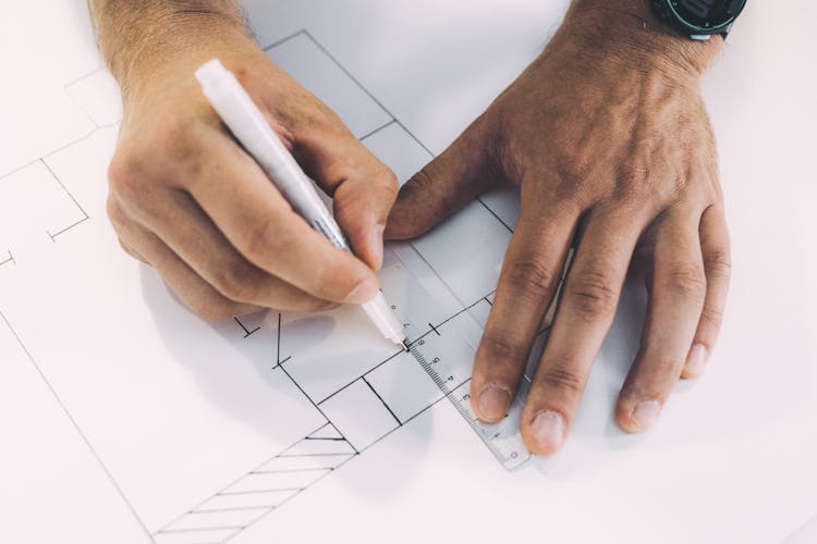 Close Up Photo Of Person Drawing Lines On Paper With Ruler And Pen