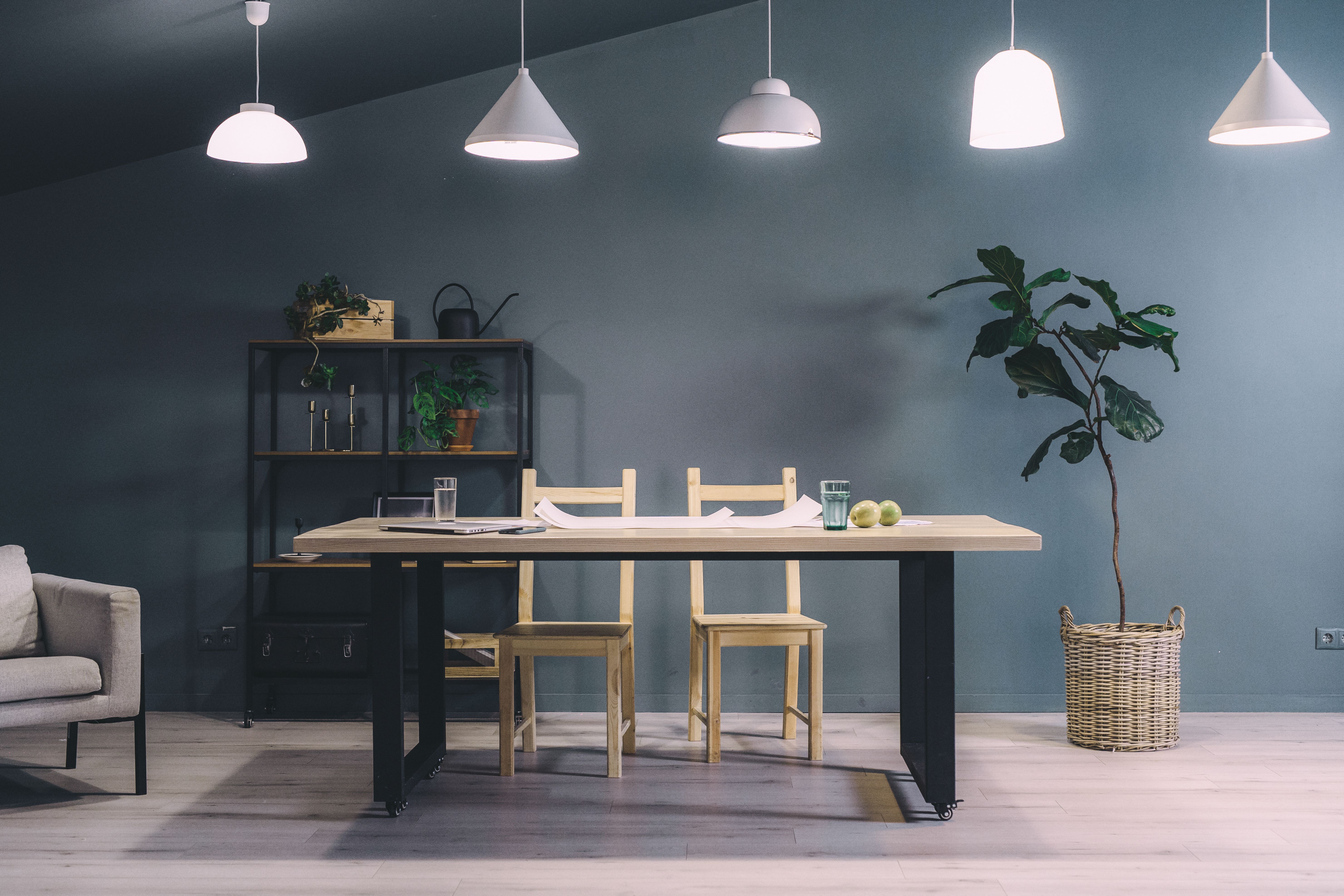 Elegant minimalist dining room with wooden chairs, table, and cozy lighting under hanging lamps.