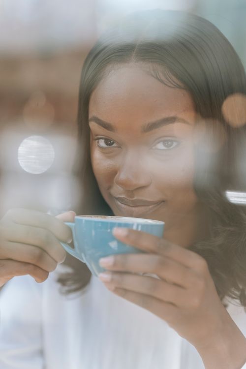 Free Close-up of a woman holding a ceramic cup with a smile, creating a warm and inviting mood. Stock Photo