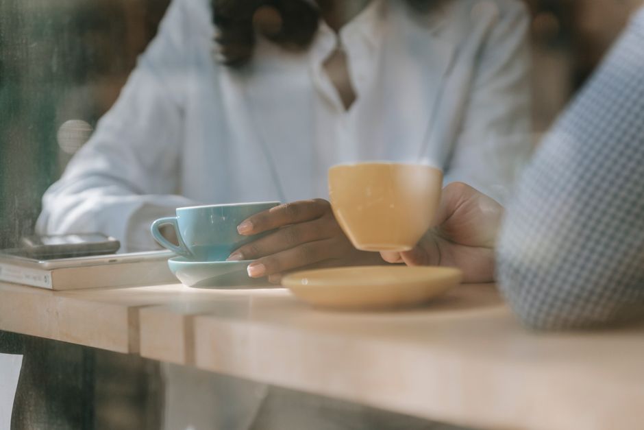 Two people enjoying coffee in a café with a serene ambiance, viewed through a window.