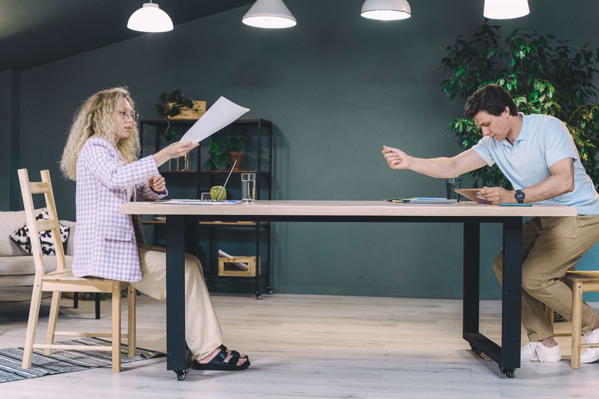 Two professionals exchanging documents in a modern office setting.