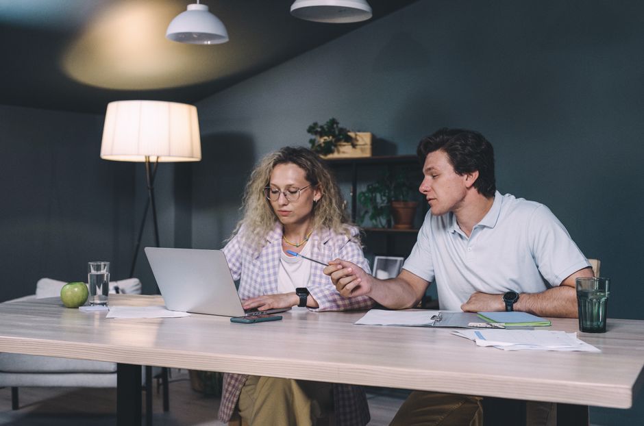 Two professionals working together at a laptop in a contemporary office setting, focusing on teamwork.