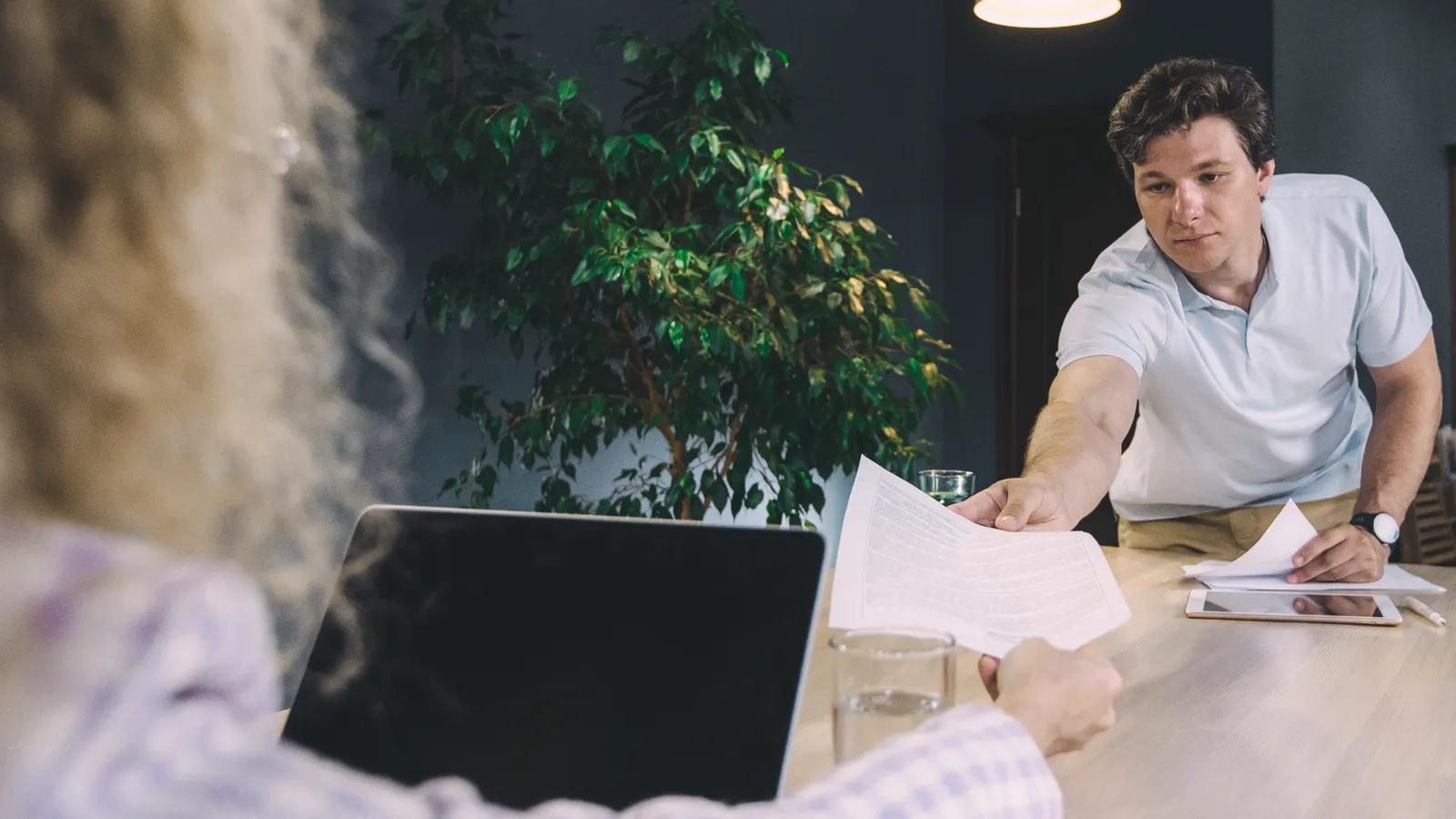 One colleague passing a printed document across a table to another