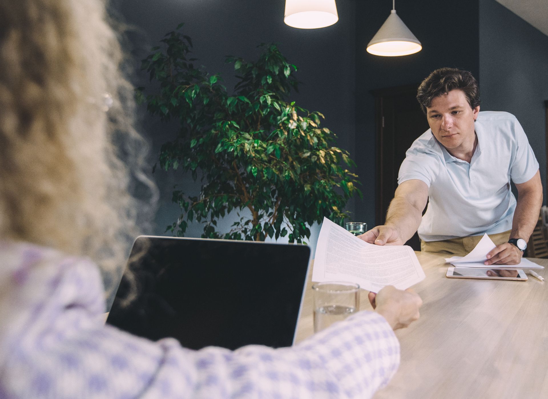 Two coworkers exchanging documents in a modern office setting.