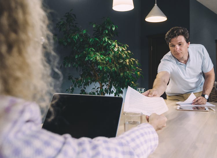 A Man Handing A Document To Another Person