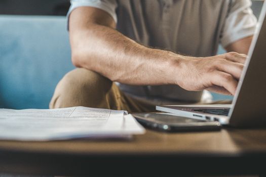 A man typing on a laptop at home, using wireless technology.
