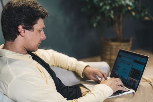 Free A young adult man deeply focused while working on a laptop indoors, sitting comfortably. Stock Photo