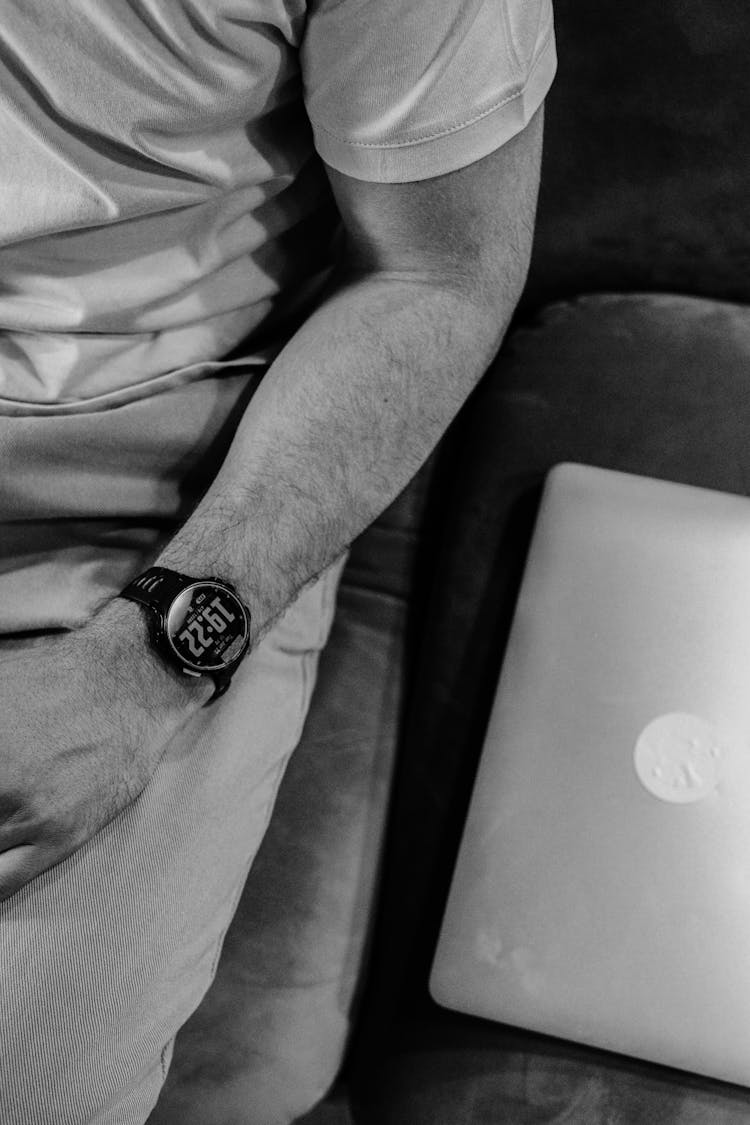 Black And White Close-up Of Man Sitting On A Sofa With A Laptop 