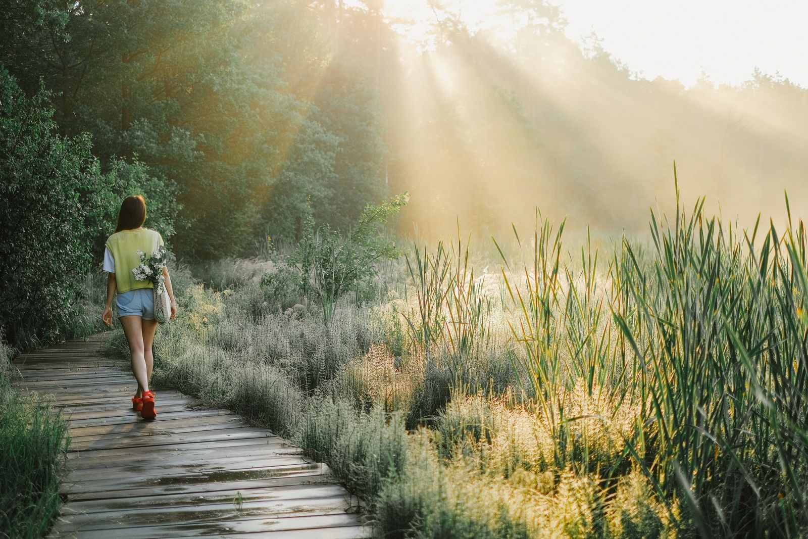 A woman walking a sunlit nature path, reflecting the whole-body wellness women pursue with GLP-1 support