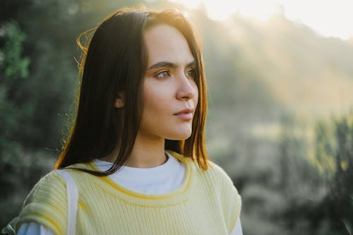 Young Brunette Standing Outside in Sunlight and Looking Away 