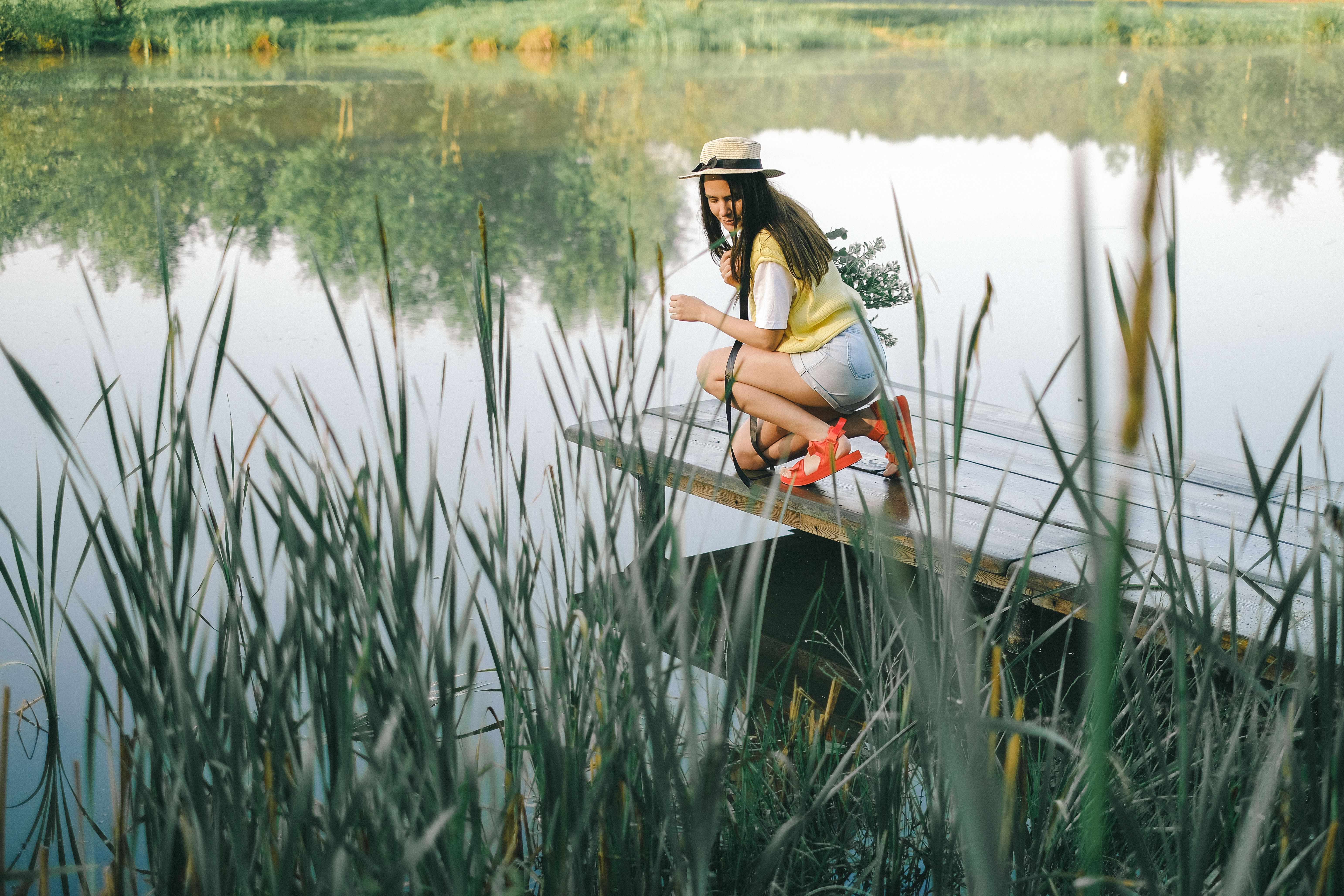 A young woman enjoying a serene moment on a wooden dock by a peaceful lake.