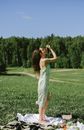 Woman in White and Green Floral Dress Standing on Green Grass Field