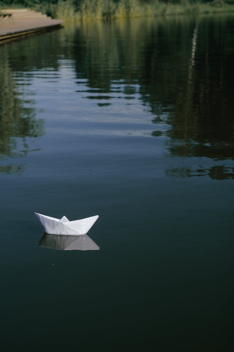 Paper Boat Floating On Calm Water