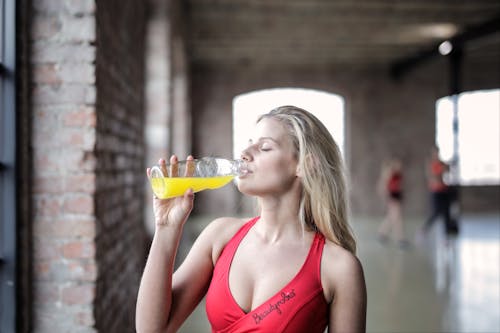 Free Selective Focus Photography of Woman in Red Tank Top Drinking Stock Photo