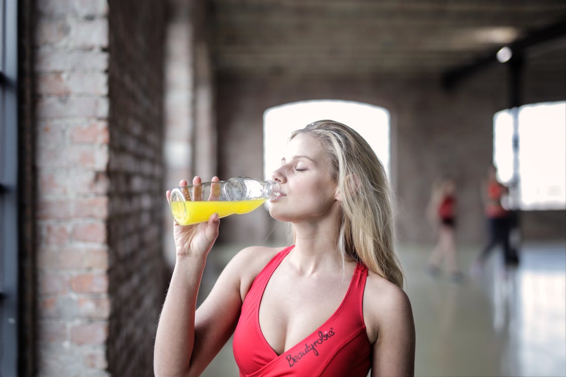 Fotografía De Enfoque Selectivo De Mujer En Rojo Tank Top Bebiendo