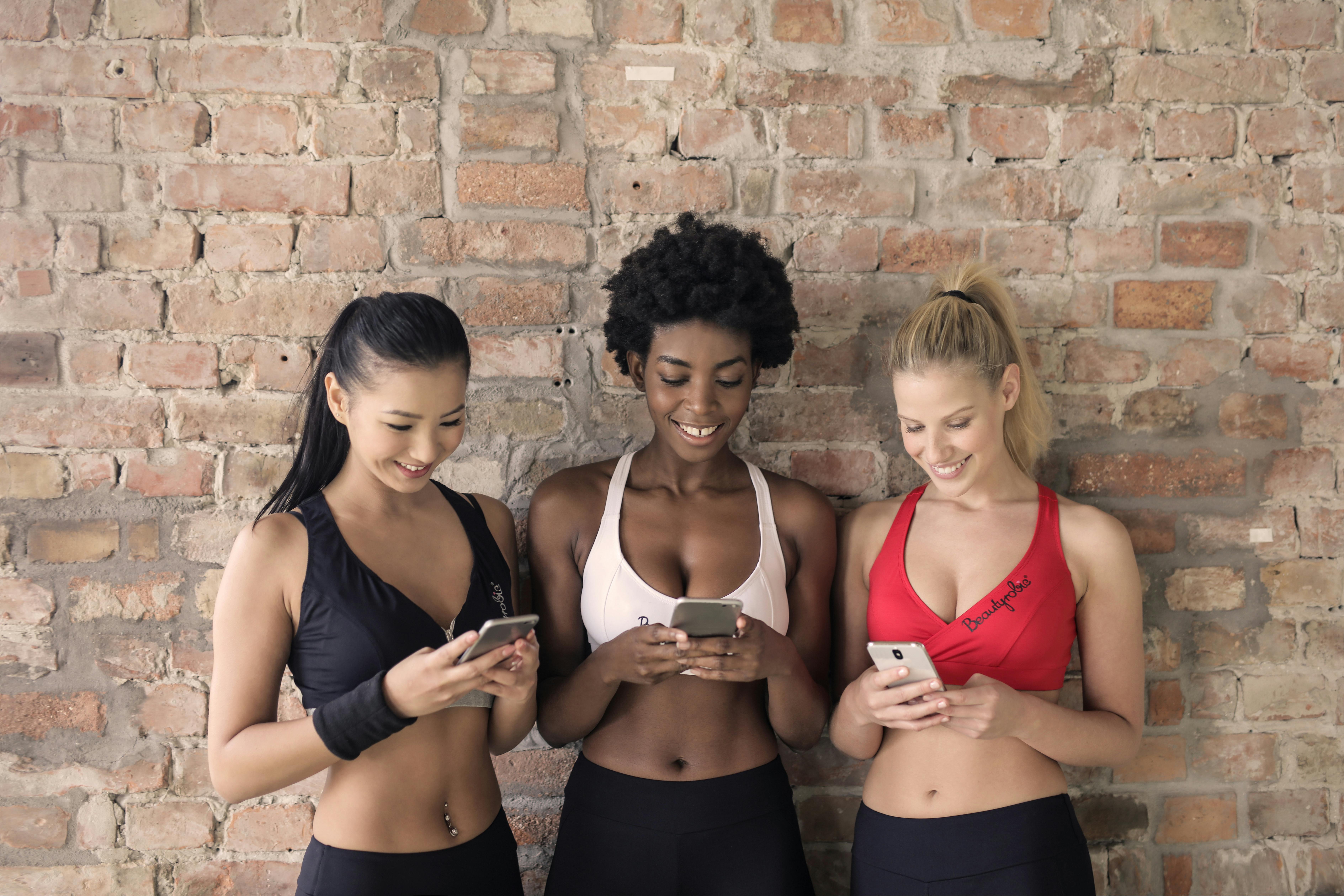 Three Woman in Assorted-color Sport Bras Holding and Watching Their  Smartphones · Free Stock Photo